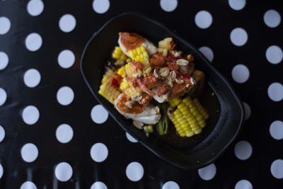 Thai papaya salad or som tum add salted eggs and yellow corn on a black background white polka dots