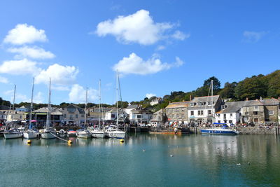 Sailboats moored in harbor against buildings in city