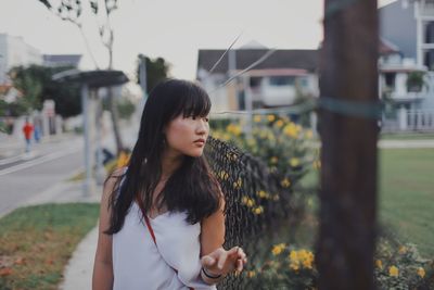 Thoughtful young woman by fence looking away