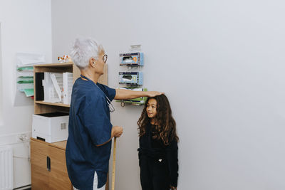 Doctor measuring girl in office