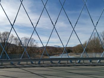 Bridge against sky seen through chainlink fence