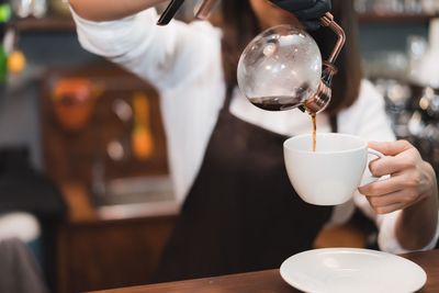 Close-up of hand pouring coffee in cup