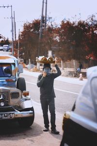 Rear view of man photographing car on street