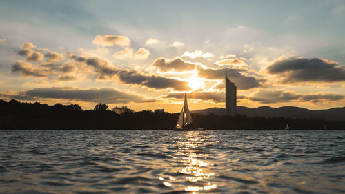 Silhouette sailboat by sea against sky during sunset