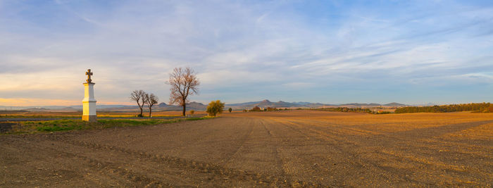 Dirt road amidst field against sky