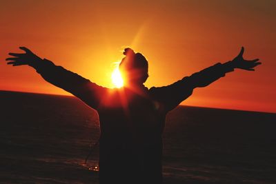 Silhouette man standing by sea against sky during sunset