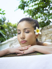 Close-up of young woman with eyes closed against trees