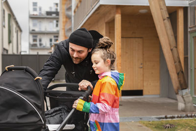 Father and daughter looking inside pram