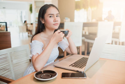 Portrait of young woman using laptop on table