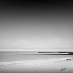 Pier at beach against sky during foggy weather