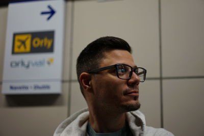Close-up of man looking away against sign on wall