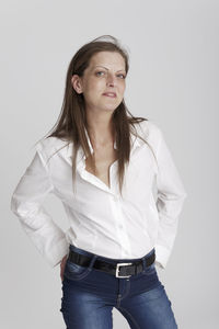 Portrait of young woman standing against white background