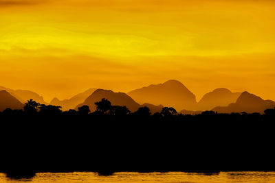 Scenic view of silhouette mountains against orange sky