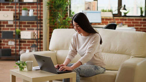 Side view of young woman using laptop while sitting at home
