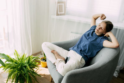 An overworked girl is sitting in a chair, resting, stretching her arms with her eyes closed