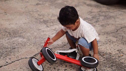 High angle view of boy playing with tricycle