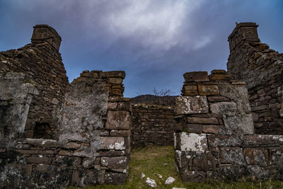 Low angle view of old ruin building against cloudy sky