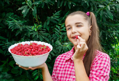 Smiling girl holding raspberries