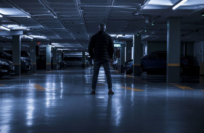 Rear view of adult man standing in underground parking lot. madrid, spain