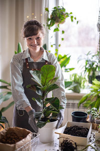 Portrait of young man standing by potted plant