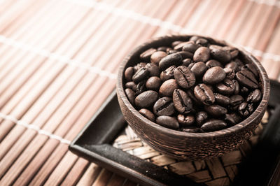 Close-up of roasted coffee beans in bowl on placemat