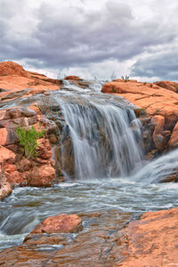 Scenic view of waterfall against sky