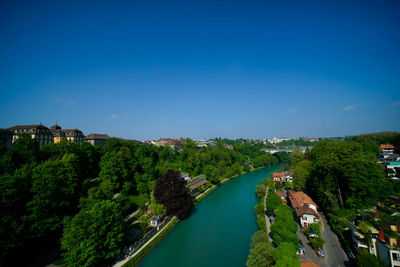 High angle view of river amidst buildings against blue sky