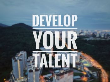 Close-up of information sign against sky in city
