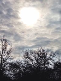 Low angle view of bare trees against cloudy sky