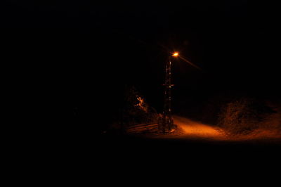 Illuminated road against sky at night