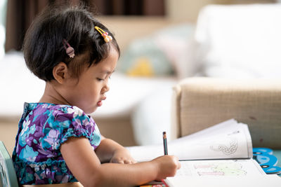 Portrait of little girl doing homework at table