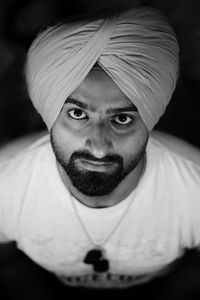 High angle portrait of young man wearing turban over black background