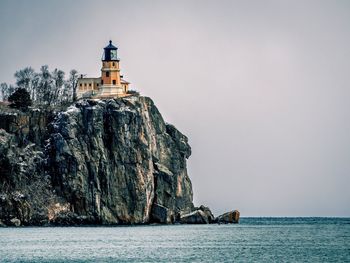 Split rock lighthouse by sea against sky