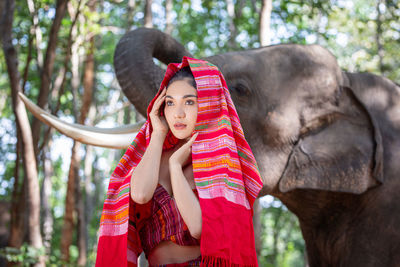 Young woman wearing scarf while standing by elephant