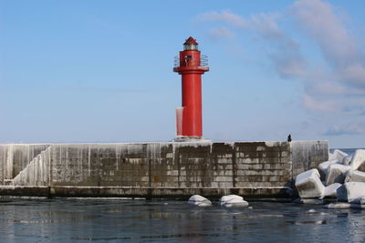 Lighthouse by sea against sky