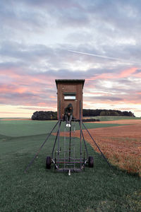 Tractor on field against sky during sunset