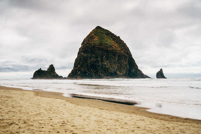 Scenic view of cannon beach against cloudy sky