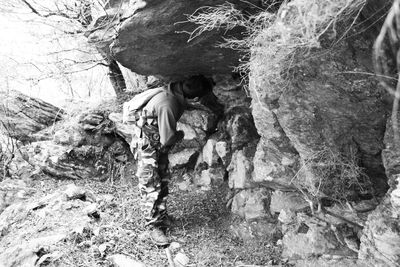 Full length of man standing on rock in forest