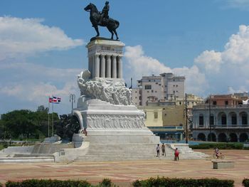 Statue in city against cloudy sky