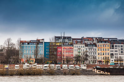 Buildings by river against sky