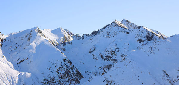 Scenic view of snow covered mountains against clear blue sky