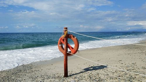 Person on shore at beach against sky