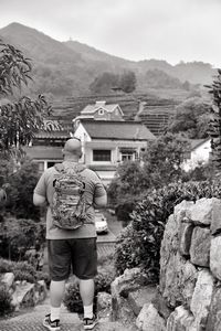 Rear view of man standing on rock by building