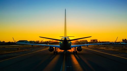 Airplane flying over road at sunset