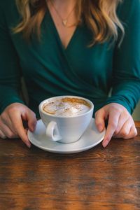 Midsection of woman holding coffee on table