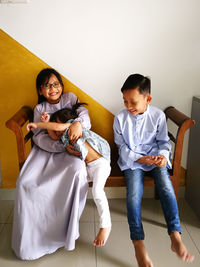 Cheerful siblings sitting on bench at home during eid-ul-fitr