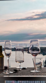 Wine glass on table against sky during sunset