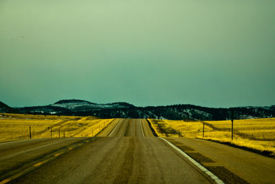 Road amidst agricultural field against clear sky