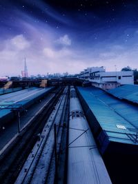 Railroad tracks in city against sky at night