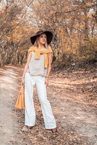 Portrait of woman wearing hat standing by tree